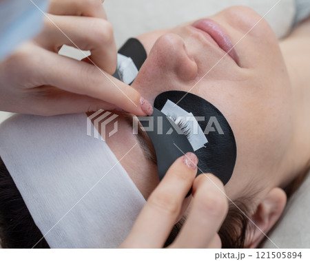 The master applies protective patches that do not let in ultraviolet rays before LED eyelash extensions. The master applies protective patches that do not let in ultraviolet rays before LED eyelash extensions. 121505894