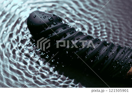 Black silicone vibrator in water. Circles on water around sex toy. Black silicone vibrator in water. Circles on water around sex toy. 121505901