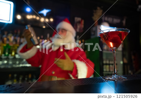Santa Claus works at the bar making cocktails in a shaker. Santa Claus works at the bar making cocktails in a shaker. 121505926