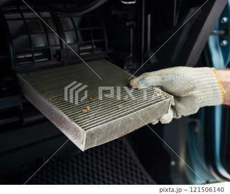 A mechanic changes the cabin air filter of a car. A mechanic changes the cabin air filter of a car. 121506140