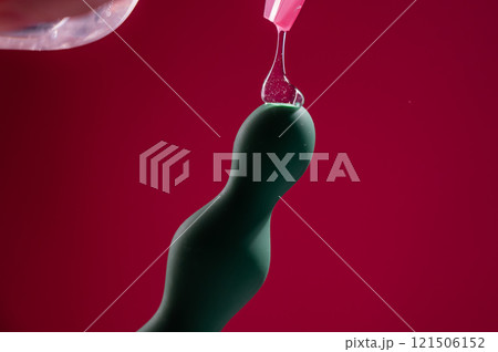 Lube pouring onto green anal beads on pink background.  121506152