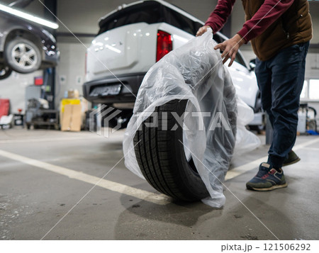 Mechanic unpacking new tires in a garage. Mechanic unpacking new tires in a garage. 121506292