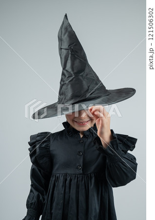 Portrait of a little Caucasian girl in a witch costume on a white background. Vertical photo. Portrait of a little Caucasian girl in a witch costume on a white background. Vertical photo. 121506302