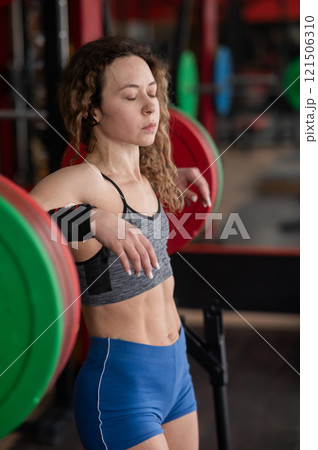 Middle aged woman posing at the barbell in the gym.  121506310