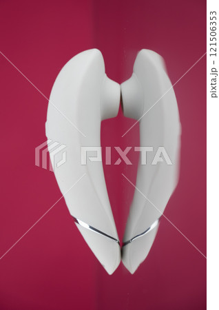 Clitoral vibrator on mirrored pink surface.  121506353