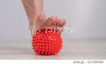 Close-up of a woman's foot on a massage ball with spikes.  121506409