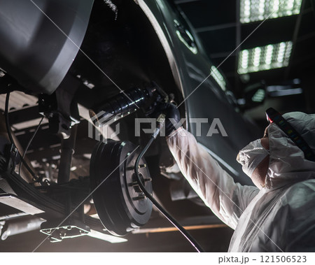 The master sprays an anti-corrosion compound on the bottom of the car.  121506523