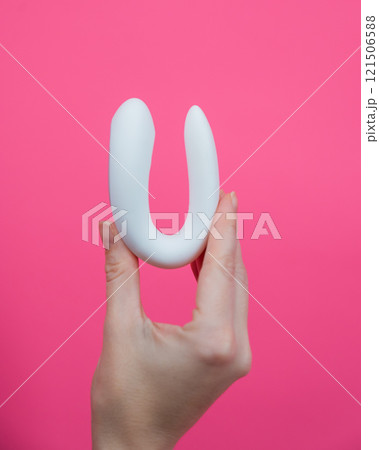 Woman holding white curved sex toy on pink background.  121506588