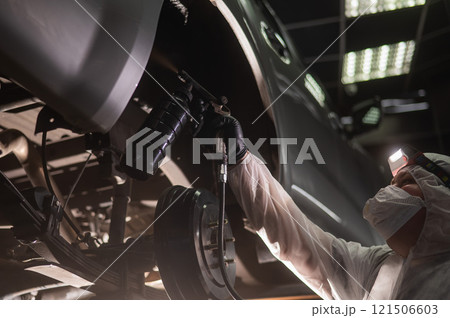 The master sprays an anti-corrosion compound on the bottom of the car.  121506603