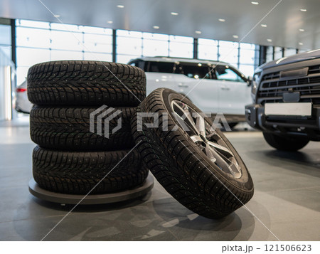 New wheels with studded tires against the background of new cars.  121506623