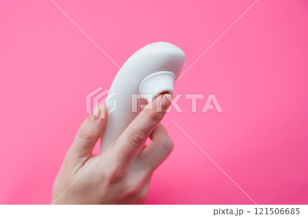 Woman holding white vacuum clitoral vibrator on pink background. Woman holding white vacuum clitoral vibrator on pink background. 121506685