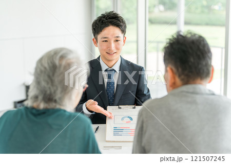 高齢者夫婦に説明・提案・案内・おすすめするビジネスマン(銀行員・資産運用・株・投資・保険) 高齢者夫婦に説明・提案・案内・おすすめするビジネスマン(銀行員・資産運用・株・投資・保険) 121507245