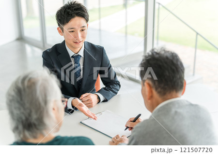 書類・契約書・申込書にサイン・署名する高齢者夫婦とビジネスマン（ファイナンシャルプランナー） 121507720