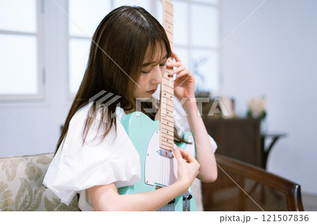 エレキギターを持つロングヘアの若い女性 エレキギターを持つロングヘアの若い女性 121507836