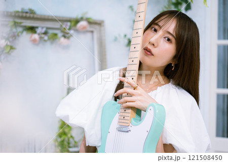 エレキギターを持つロングヘアの若い女性 121508450
