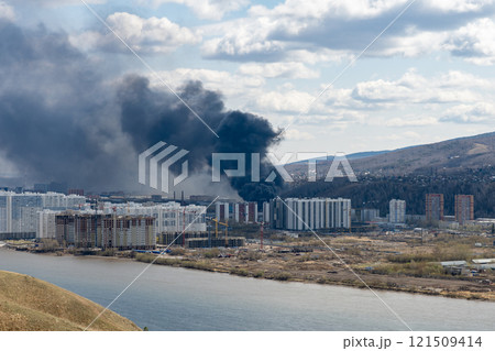 Black smoke from a fire in a city on the other side of the river. 121509414
