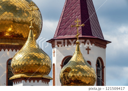 Golden dome of the church with a golden cross against the background of a cloudy sky. 121509417