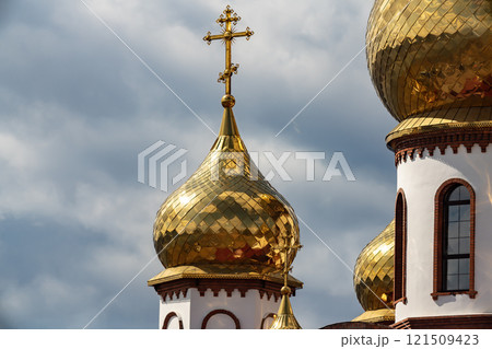 Golden dome of the church with a golden cross against the background of a cloudy sky. Golden dome of the church with a golden cross against the background of a cloudy sky. 121509423