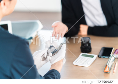 自宅に保管していた腕時計を買取業者で見積もる若い男性　顔無し 121509821