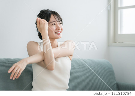 家のソファで軽くストレッチやヨガをする若いアジア人女性（モーニングルーティーン） 121510784