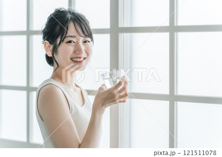 家で水・ミネラルウォーター・白湯をコップで飲むリラックスした女性 121511078
