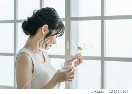 服薬・薬を飲む頭痛・体調不良のアジア人女性（困る・悩む） 121511165