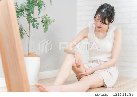 家で太もものマッサージをして浮腫み対策をする笑顔の日本人女性 家で太もものマッサージをして浮腫み対策をする笑顔の日本人女性 121511283