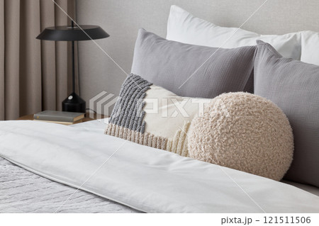 A Modern and Cozy Bedroom Incorporating Stylish Decorative Pillows and an Attractive Lamp 121511506