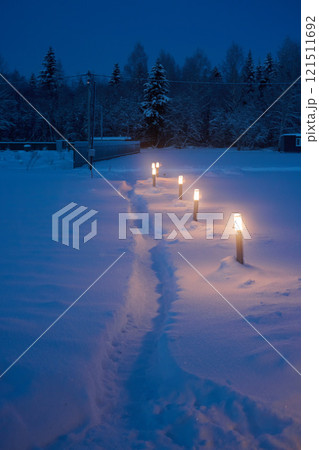 A Serene Winter Pathway That is Beautifully Illuminated by Lanterns Shining in the Snow A Serene Winter Pathway That is Beautifully Illuminated by Lanterns Shining in the Snow 121511692