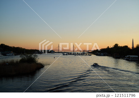 A Beautiful and Serene Sunset Over the Calm River, Complimented by a Scenic Bridge Nearby 121511796