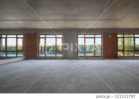 A modern minimalist room with large windows that invite natural light, creating brightness 121511797
