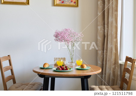 Charming and Inviting Breakfast Table Setup Featuring Fresh Fruits and Beautiful Flowers 121511798