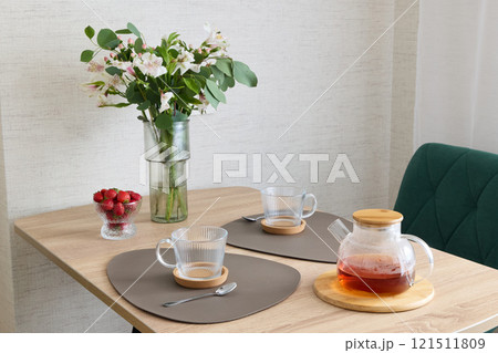 A Cozy and Inviting Tea Setup Featuring Beautiful Flowers and Fresh Juicy Strawberries A Cozy and Inviting Tea Setup Featuring Beautiful Flowers and Fresh Juicy Strawberries 121511809