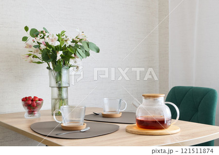 A Cozy and Inviting Dining Table Setup Featuring Tea and Fresh Flowers for Decoration A Cozy and Inviting Dining Table Setup Featuring Tea and Fresh Flowers for Decoration 121511874