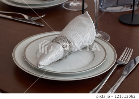 An Elegant Table Setting Featuring a Beautifully Arranged Decorative Napkin and Dinnerware 121512062