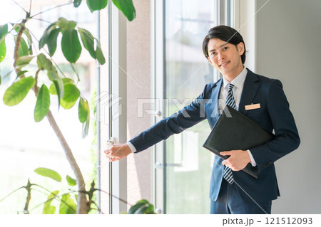 窓・ドア・サッシ・ガラス戸・鍵を案内するビジネスマン（樹脂サッシ・省エネ基準） 121512093