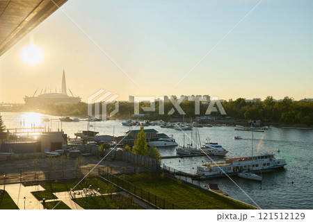 A Serene and Picturesque Sunset Over the River Featuring Boats Amidst a Beautiful City Skyline 121512129