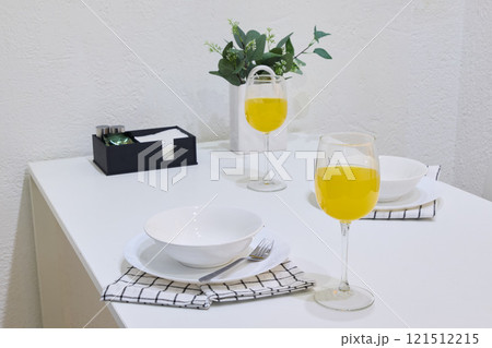 An Elegant Dining Table Setup with Bright Yellow Drinks and Fresh Greenery Accents 121512215