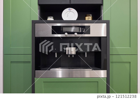 A contemporary and modern builtin coffee machine located in a stylish green kitchen setting A contemporary and modern builtin coffee machine located in a stylish green kitchen setting 121512238