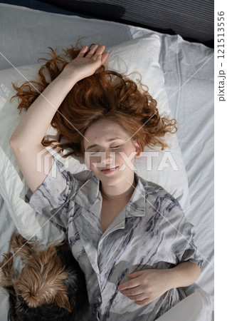 A woman is relaxing in bed with her beloved dog, enjoying the peaceful atmosphere of the moment A woman is relaxing in bed with her beloved dog, enjoying the peaceful atmosphere of the moment 121513556