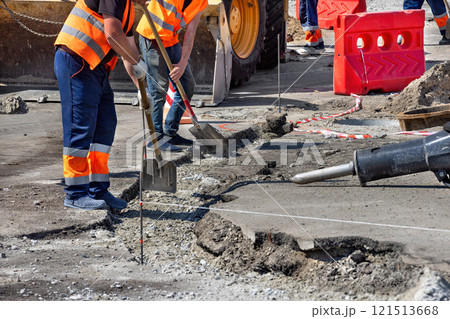 Construction workers repairing pavement in a busy urban area during daylight hours 121513668