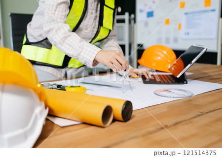 Businessman hand working and laptop with on on architectural project at construction site 121514375