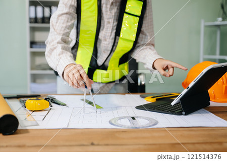 Businessman hand working and laptop with on on architectural project at construction site 121514376
