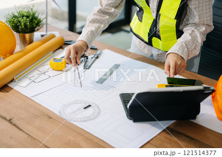 Businessman hand working and laptop with on on architectural project at construction site 121514377