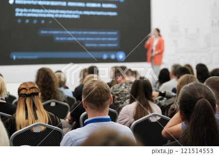 Audience attending a presentation with speaker on stage and displayed content screen 121514553