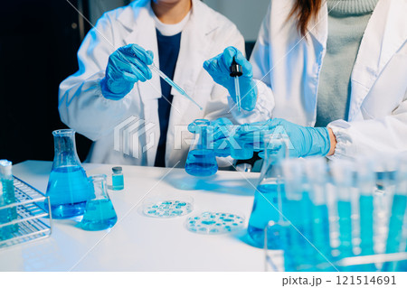 scientists in lab coats conducting research, handling glassware, and working with chemicals scientists in lab coats conducting research, handling glassware, and working with chemicals 121514691