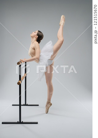 Ballet dancer practicing at the barre in a minimalist studio setting Ballet dancer practicing at the barre in a minimalist studio setting 121515670