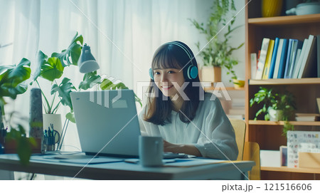 部屋でノートパソコンを使いながらオンライン授業を受ける女子大生 121516606