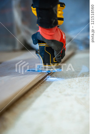 Close Up of Woodworking with Handheld Router and Safety Glove 121518560