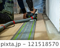 Person Using Track Saw for Wood Flooring Installation Indoors 121518570
